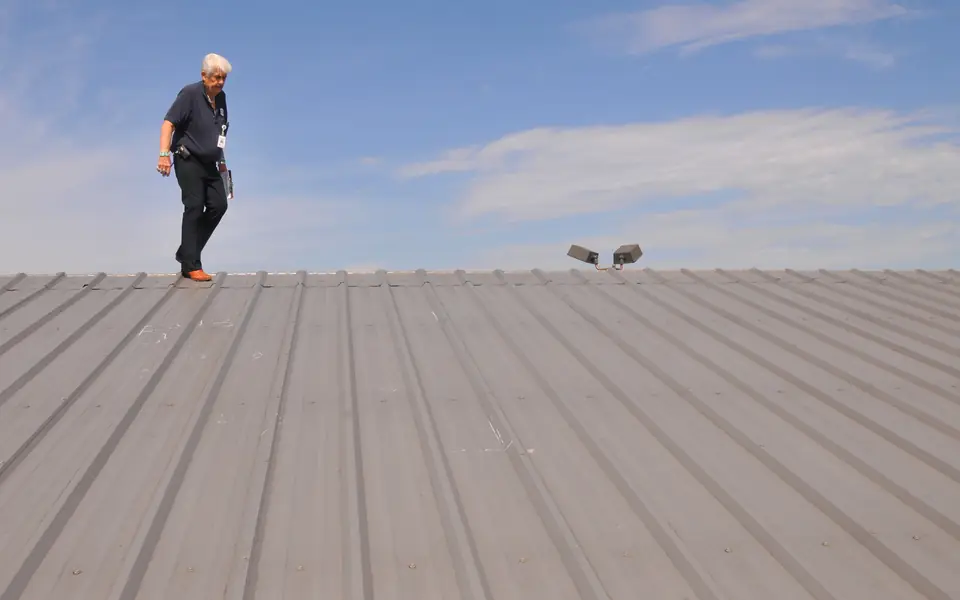 Person walking a metal roof to check for hail damage